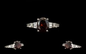 Red Garnet Solitaire Style Ring, a 4.25ct oval cut garnet solitaire, accented by two tapered