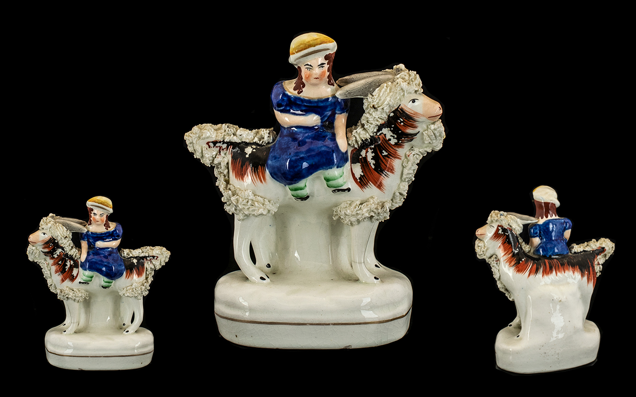 Small Antique Staffordshire Figure of a Girl riding a goat with applied fritting finish.