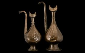 Pair of Middle Eastern Antique Embossed Copper Ewers with shaped spouts and crescent shaped tops.