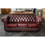 Three Seater Chesterfield Sofa, covered in a burgundy leather and supported on castors.