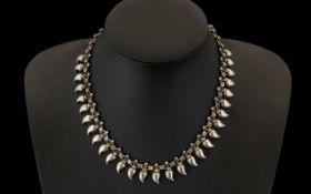 An Antique Silvered Metal Indian Type Necklace with hanging shaped Lotus buds from the chain.