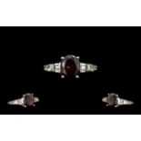 Red Garnet Solitaire Style Ring, a 4.25ct oval cut garnet solitaire, accented by two tapered