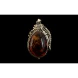 A Large Modern Amber Pendant. Set in a silver floral mount. Measures 88 by 50mm including bale.