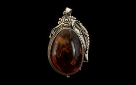 A Large Modern Amber Pendant. Set in a silver floral mount. Measures 88 by 50mm including bale.