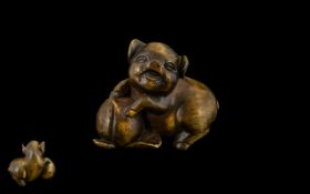 A Japanese Carved Boxwood Netsuke In The Form of a Pig Frolaking with Fruit,