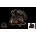 An Oriental Boxwood Netsuke in the form of a Monkey sitting on a Horse. Realistically carved.