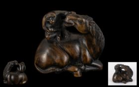 An Oriental Boxwood Netsuke in the form of a Monkey sitting on a Horse. Realistically carved.