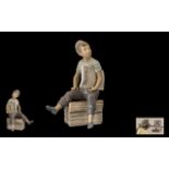 Nao Figure of a Paper Boy Early porcelain figure of a Newspaper Boy Seller Sitting on a Box.