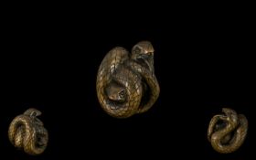 An Oriental Boxwood Netsuke in the form of a snake coiled around a frog. Signed to underneath.