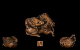 An Oriental Boxwood Netsuke in the form of two wild boars, signed to base.