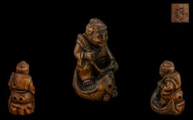 An Oriental Boxwood Netsuke in the form of a fisherman and his catch, signed to base.