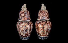Two Imari Jars and Covers of typical form, the covers surmounted by Foo Dogs,