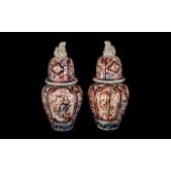 Two Imari Jars and Covers of typical form, the covers surmounted by Foo Dogs,