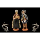 Pair of Pottery Figures of a Farmer and Wife, dressed in traditional garb, signed M.