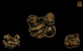 An Oriental Boxwood Netsuke in the form of a monkey fighting an octopus. Signed to underside.