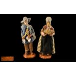 Pair of Pottery Figures of a Farmer and Wife, dressed in traditional garb, signed M.