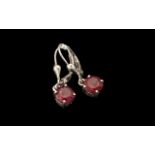 Pair of Ruby Drop Earrings, two round cut solitaires of rubies of an excellent shade of red,