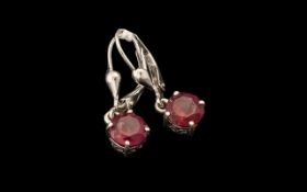 Pair of Ruby Drop Earrings, two round cut solitaires of rubies of an excellent shade of red,