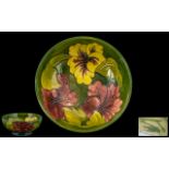 William Moorcroft Signed Tubelined Footed Bowl, 'Hibiscus' pattern, various colours on green ground.