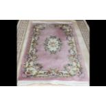 Traditional Rug in shades of pink and cream, with central oval decorative pattern and fringed edges.