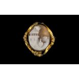 Antique Victorian Cameo Brooch depicting a lady outside a house, set in a gold metal floral frame.