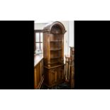 A Modern Yew Wood Bookcase with a shell design pediment above three fixed shelves and storage base.