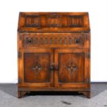 A reproduction oak bureau, fall front with three linen-fold panels, single drawer and two panelled