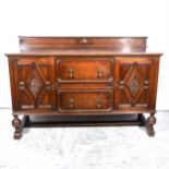 An oak Jacobean revival, sideboard, fitted with two deep drawers, flanked by cupboards, each with