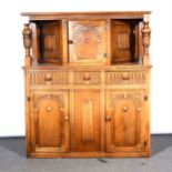 A reproduction oak court cupboard, the upper section with an arcaded panelled door, canopy section