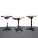 A pair of cast iron tables, replaced wooden tops, column supported by tripod bases, diameter 61cm;
