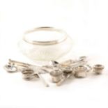 A glass fruit bowl with silver rim, silver and plated napkin rings and assorted flatware.