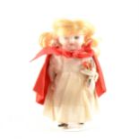 An early 20th Century French pocket full bisque miniature doll, in 'Little Red Riding Hood' outfit