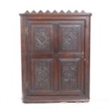 A carved oak hanging corner cupboard,