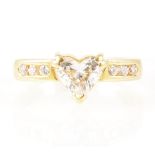 A heart shaped diamond ring with diamond shoulders.
