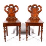 A pair of early Victorian mahogany hall chairs