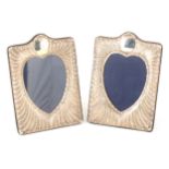 A pair of rectangular silver photograph frames with heart shaped centre.