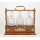 Edwardian oak three-bottle tantalus with key,