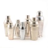 Seven plain metal cocktail shakers, various sizes.