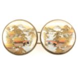 A pair of Japanese satsuma buckles, depicting scenes of mountains