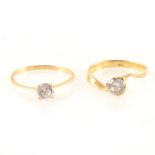 Two yellow metal solitaires marked 750 set with synthetic white stones.