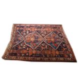 An old Caucasian rug, two joined medallions on a patterned blue field, narrow borders, torn and