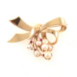 A yellow metal ribbon design brooch set with seven cultured pearls and five rubies.