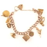 A 9 carat rose gold hollow curb link bracelet with eleven charms attached.