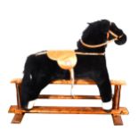 A black plush rocking horse, Mama's & Papa's, on a beechwood trestle, length 118cm.