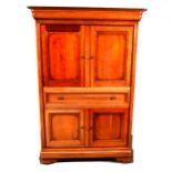 A cherry wood finish home entertainments cabinet, moulded cornice piece, two panelled doors over a