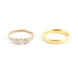 A 22 carat yellow gold wedding band and diamond three stone ring.
