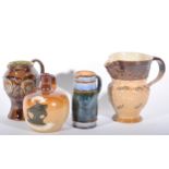 Four Doulton stoneware jugs, a relief moulded harvest jug with cherubs, grapes and vines,