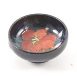 A small Moorcroft Pottery pin dish, floral design, navy ground, 7.5cm diame