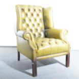 A modern leather wingback chair in the Georgian style, buttoned and close s