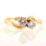 A diamond two stone crossover ring, the brilliant cut stones claw set in a